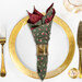 A top down shot of a place setting with the reversible muted green rose fabric of the napkin faced out.
