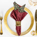 A top down shot of a place setting with the reversible tonal red leaf fabric of the napkin faced out.