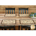 A wide shot of the four placemats on a wooden table with coordinating cloth napkins off to the side on a stack of plates.
