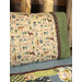 An angled shot of the Magic Pillowcase in tan and green, staged on a bed with a matching patchwork quilt in a cabin setting.