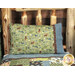 A shot of the Magic Pillowcase in green, brown, and blue, staged on a bed with a matching patchwork quilt in a cabin setting.