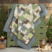 The Easy as ABC and 123 Quilt - Lodge Life quilt featuring a patchwork design in tones from nature like blue, green, and brown, artfully draped over a green armoire next to green trees and coordinating decor.
