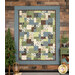 The Easy as ABC and 123 Quilt - Lodge Life quilt featuring a patchwork design in tones from nature like blue, green, and brown, hanging from a wood-paneled wall next to green trees and coordinating decor.