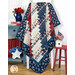 The Standing Strong quilt draped over a chair, with red, white, and blue patterns, alongside flowers and decor.