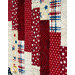 Close-up of a quilt featuring a patchwork design with red, cream, and blue fabrics, including stars.