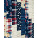 A patchwork quilt featuring red, white, and blue patterns, including stars and plaid designs.