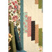 A close up on the left side of the quilt, demonstrating fabric, piecing, border, and binding details. Books with covers in coordinating colors peek into frame from the left side.