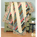 The finished 28th Floor Quilt artfully draped over an olive green dresser, with a black stool and coordinating greenery nearby.