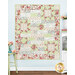 The completed Comfort of Psalms Quilt Kit, colored in green, blue, and pink fabrics from the My Victorian Garden collection, staged on a pastel blue paneled wall and staged with coordinating furniture and decor.