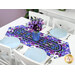 The completed Easy Striped Table Runner colored in vibrant purple floral fabrics from the Pansy Perfection collection, staged on a clean white table with coordinating table ware.