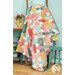 The completed Picnic Quilt colored in vibrant, peach, gold, aqua, and teal fabrics from the Tango collection by Moda Fabrics. The project is hung on a rustic wooden quilt ladder and staged with coordinating flowers and furniture.