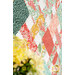 A stylized close up on the patchwork, showing fabric color and print details; coordinating flowers peek into frame from the left side.