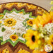 A stylized close up on the topper demonstrating fabric prints and colors; coordinating flowers peek into frame from the right side.