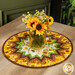 The completed topper staged on a rustic wood table with a jar in the center full of coordinating flowers.