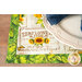 A close up on a placemat demonstrating fabric color and detail; a plate with a coordinating napkin peek into frame from the upper right corner.