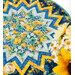 A shot of the completed table topper staged on a white table with out of focus daisies and sunflowers in the foreground.