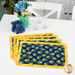 A shot of the four completed summer-themed overlapping placemats in navy and yellow floral prints, staged on a white table with coordinating decorative flowers.