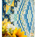 A close up angled shot across the middle of the quilt, with coordinating flowers in the foreground.