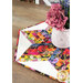 A stylized shot of the topper on a wooden table, topped with a white vase of decorative flowers in coordinating colors.