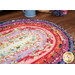 A close up on the Jelly Roll Rug demonstrating print and color details on the fabrics. Coordinating decor peeks into frame from the top of the image.