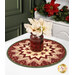 The completed Point of View Kaleidoscope Folded Star Table Topper colored in festive red and cream fabrics from the A Vintage Christmas collection, staged on a white table with a coordinating vase of flowers resting in the center of the topper.