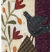 A super close up on an appliqué bird beside flowers and the purple border of the quilt, demonstrating fabric color, patterns, and top quilting details.