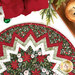 A super close up on the Berry & Pine Point of View Folded Star Table Topper, demonstrating fabric colors and details on the center and folded points. Coordinating decor peek into frame from above.