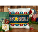 The finished July pillow wrap kit, a navy blue wrap with red and blue scalloped borders and appliqué letters that read 