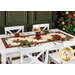 The completed table runner colored in cream, red, and green floral Christmas fabrics from the Glisten collection, staged on a white table with coordinating gold-rimmed plates, cloth napkins, florals, and a decorated Christmas tree.