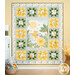 The completed Sunny Safari Patchwork Quilt colored in green, white, and yellow fabrics, hung on a yellow-paneled wall and bordered by coordinating baby décor.
