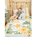 A shot of the quilt staged on a cabin bed with a young boy laying on top, posing with a coordinating Sunny Safari pillow and a stuffed elephant plushie.