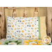 A shot of the Magic Pillowcase in white, yellow, and green, staged on a bed with a matching patchwork quilt in a cabin setting.
