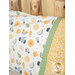 An angled shot of the Magic Pillowcase in white, yellow, and green, staged on a bed with a matching patchwork quilt in a cabin setting.