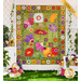 Photo of a green, pink, purple, and yellow floral quilt hanging on a white paneled wall with white lattices on either side with baskets of colorful flowers and climbing plants