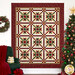 The completed Christmas in Coeur d'Alene Quilt, colored in red, green, cream, and white fabrics from the Stof 2025 collection, hung on a white paneled wall and staged with coordinating Christmas decor.