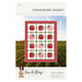 The front of the Strawberry Basket pattern featuring a digital image of the finished quilt overlaid over an image of a field.