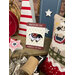 The American Ewe Magnetic Needle Minder with its paper packaging insert, staged with coordinating patriotic decor.