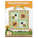 Front cover of the Pieceful Patchwork - August pattern featuring the completed sunflower and bee-themed wall hanging staged on a white wall with coordinating decor and yellow banners.