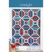 The front of the Limelight pattern featuring a red, white, and blue quilt with strips surrounding sawtooth stars, hung on a white wall.