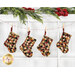The four completed Fast Fusible Patchwork Stockings colored in the A Vintage Christmas collection, hung on a string by clothespins in front of white wooden decor with Christmas garland at the top.