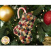 A shot of a tiny stocking with candy and ornaments poking out from the top, hung from the branch of a Christmas tree to demonstrate scale.