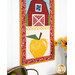 A close up on the bottom yellow apple block of the project, with part of the barn peeking into frame from the top. Coordinating florals and apple decor sit below the project.
