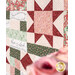 An angled shot of the quilt's patchwork, with an out-of-focus rose peeking into frame.