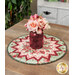 A shot of the table topper staged on a wooden table with a red vase of roses displayed in the center of the project.
