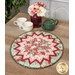 The completed Point of View Folded Star Table Topper colored in mint green, red, and pink floral fabrics from the Regal Rose collection. The topper is staged on a wooden table with coordinating red and green tableware and flowers.