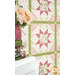 An angled shot of the quilt bordered by a vase with coordinating pink florals, demonstrating fabric, piecing, sashing, border, and binding details.