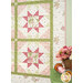 A shot of the right side of the quilt staged next to a green stool with a basket of flowers and spool of coordinating pink ribbon.
