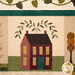 A close up on the top middle block of the quilt, showing fabric, color, and appliqué details on a maroon house with a blue door.