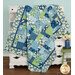 The completed Easy as ABC and 123 Quilt colored in blue, green, and white fabrics from the Blue Harmony collection, artfully draped over a white armoire and staged with coordinating flowers.