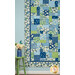 A closer look at the quilt, staged with a coordinating stool and flowers, demonstrating fabric color, detail, and patchwork layout.